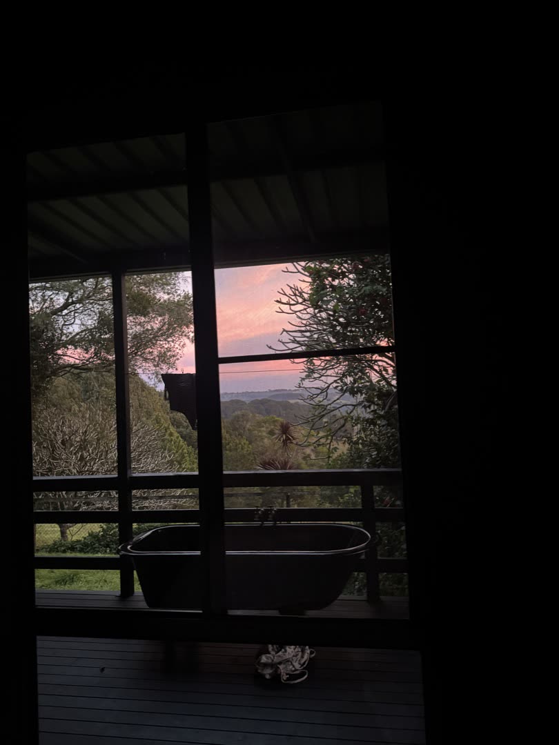 Outdoor bath through the bedroom window at sunset, soft pink sky
